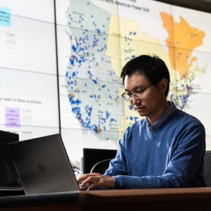 A man looks at the computer monitor with a map in the background.