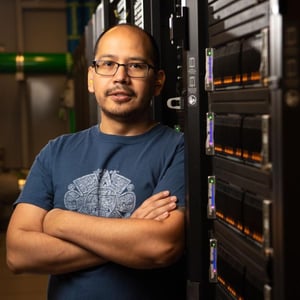 Photograph of Daniel Mejia Rodriguez standing near a powerful computer.