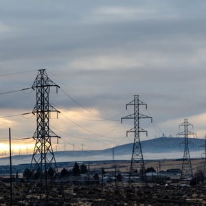 Alt text: Photograph shows transmission power line towers against a cloudy sky.
