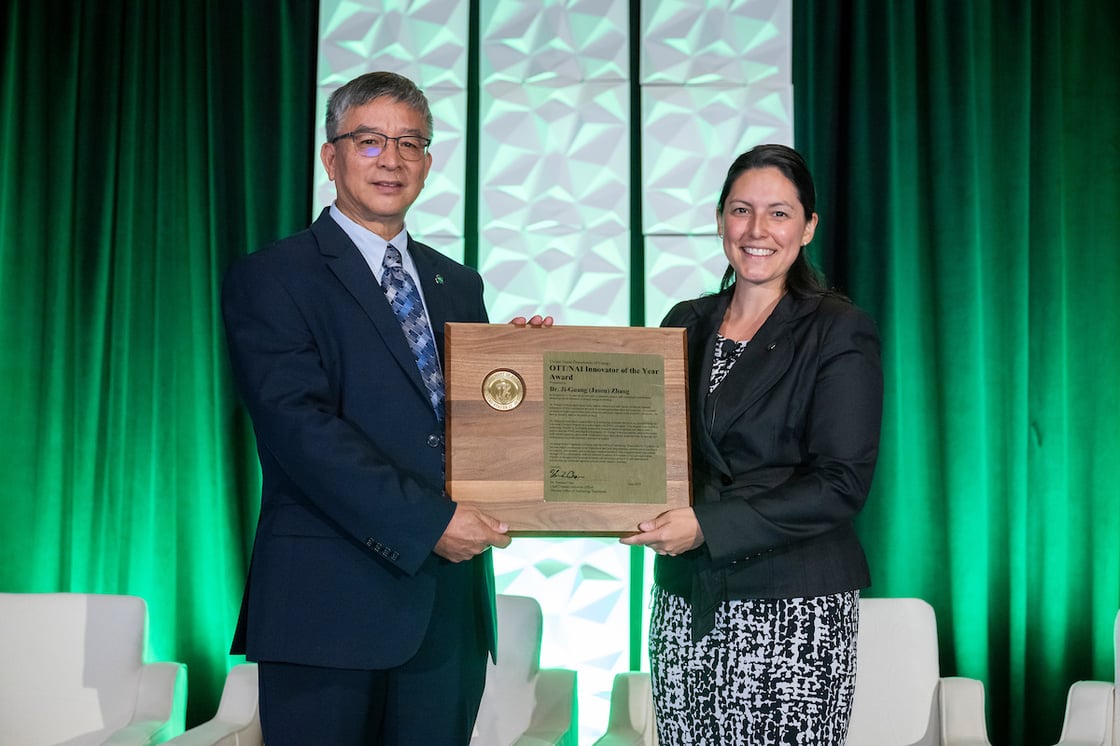 Photo of Jason Zhang holding his inventor award with Vanessa Pena.