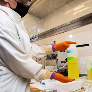 Photo of a scientist holding a bottle of tank waste with cesium removed.