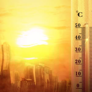 Image of a thermometer and very warm buildings to illustrate rising temperatures.