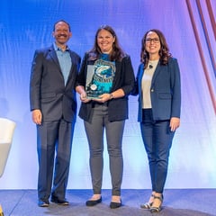 Photograph shows Alison Colotelo holding an award and standing on stage with two people from the National Hydropower Association.