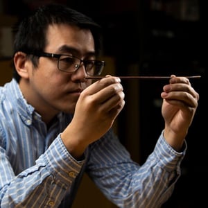 Photograph shows scientist Xiao Li holding a piece of metal wire.